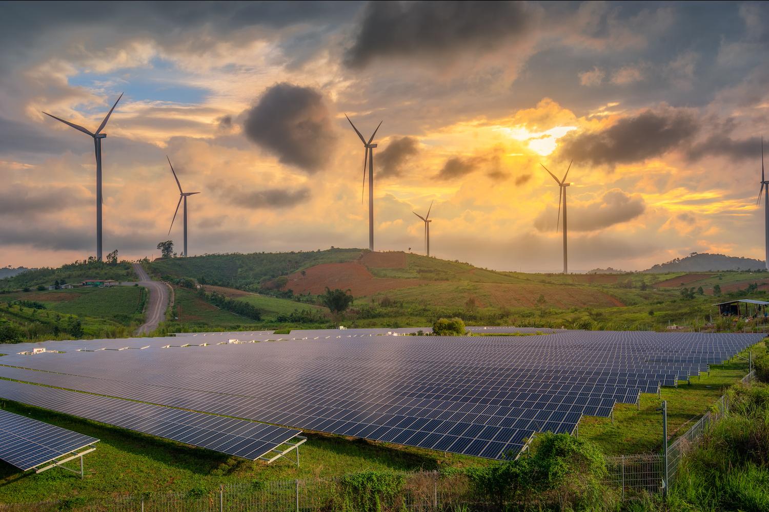 Clean Energy - Solar Panels and Wind Turbines in a field at sunset